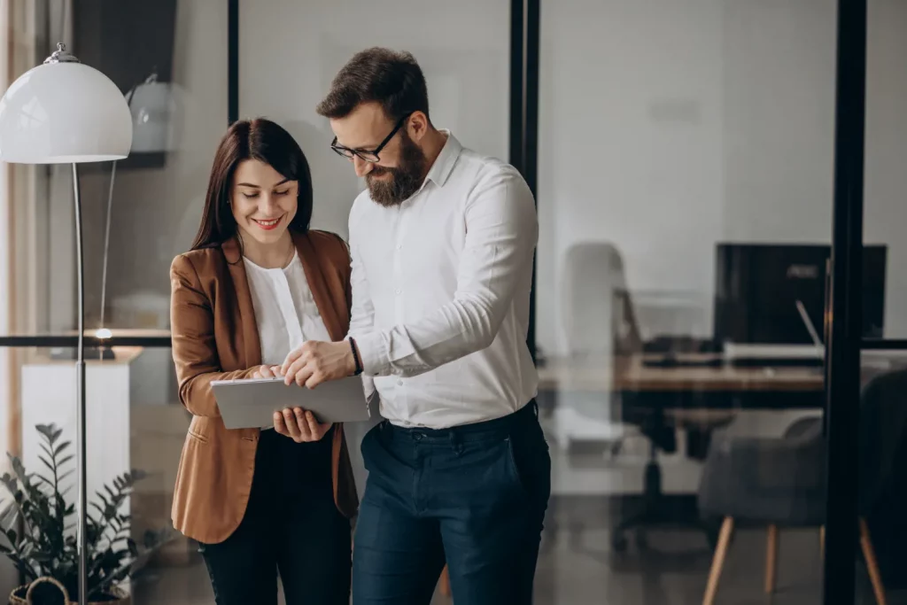 Homme et femme debout souriant regardant une tablette à deux